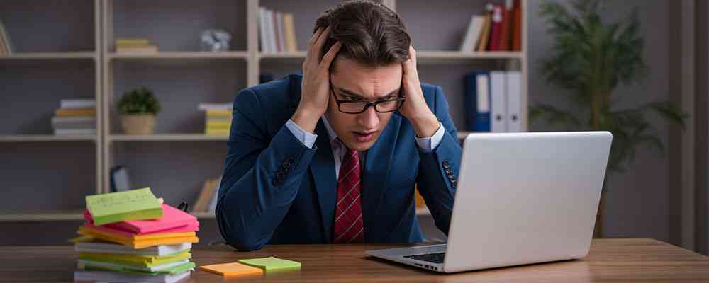 Frustrated employee at desk showing signs your IT is holding you back with slow computer